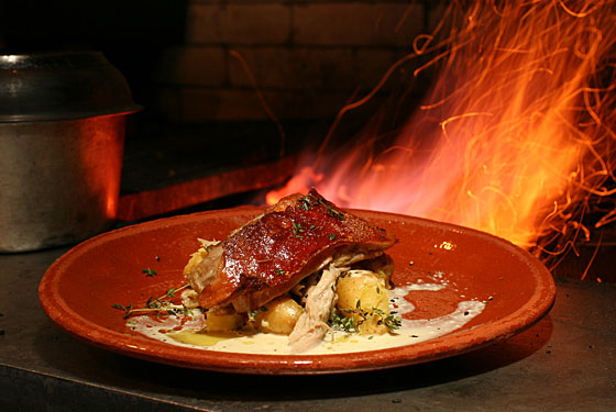 Spit-roasted pig and potatoes cooked over a fire at Peasant.