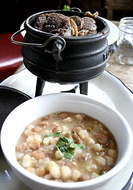 
Slow-cooked stew of the day, shown here with Cornish hen, served in a traditional
African three-legged cast iron pot.


