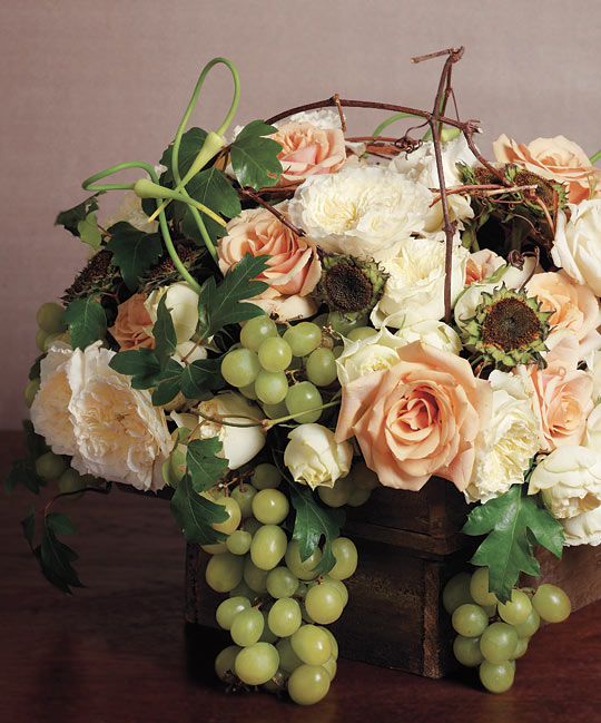 Centerpiece of garden roses sunflower cores grape ivy and muscat grapes 